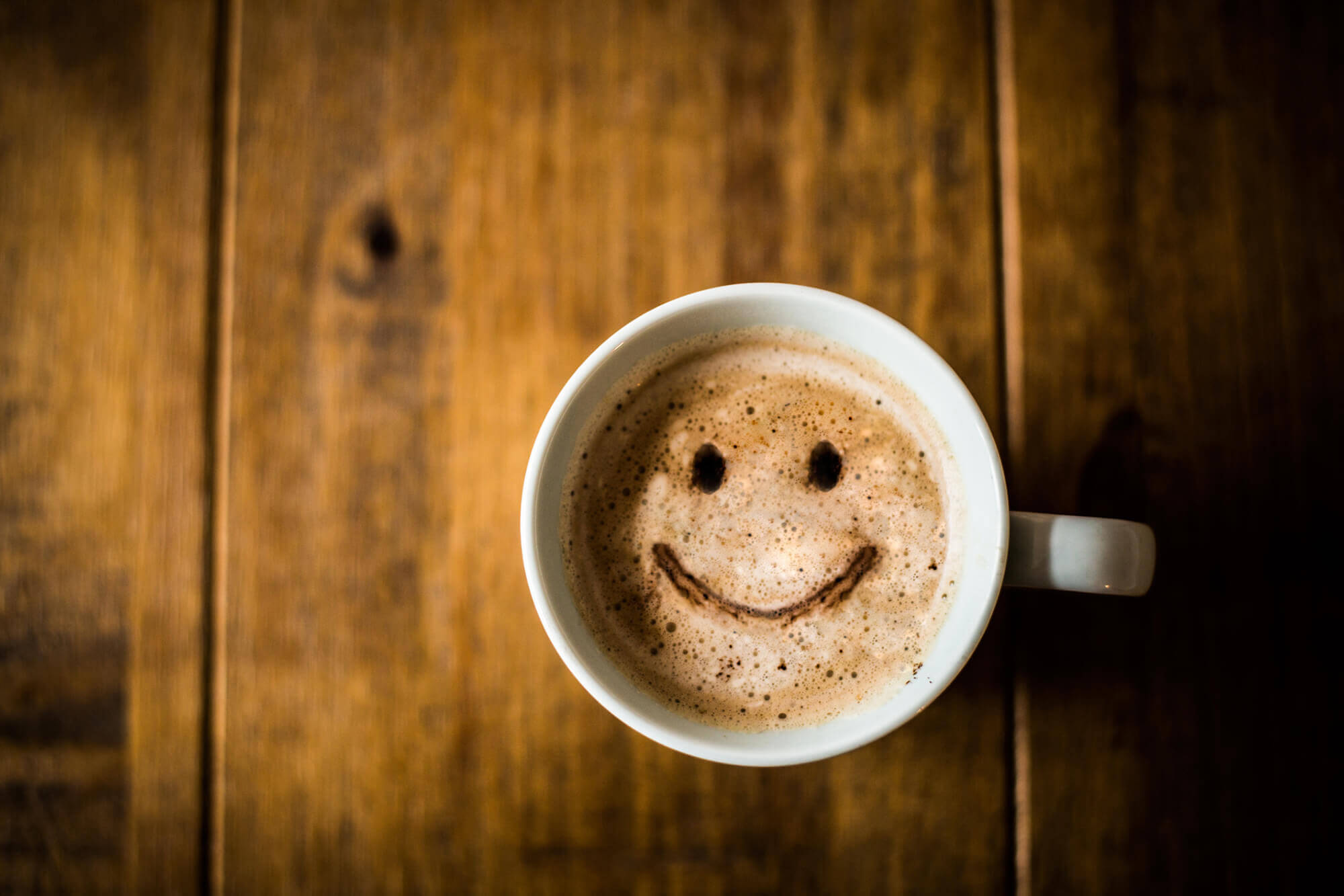 A cup of coffee with a smiley face drawn on it