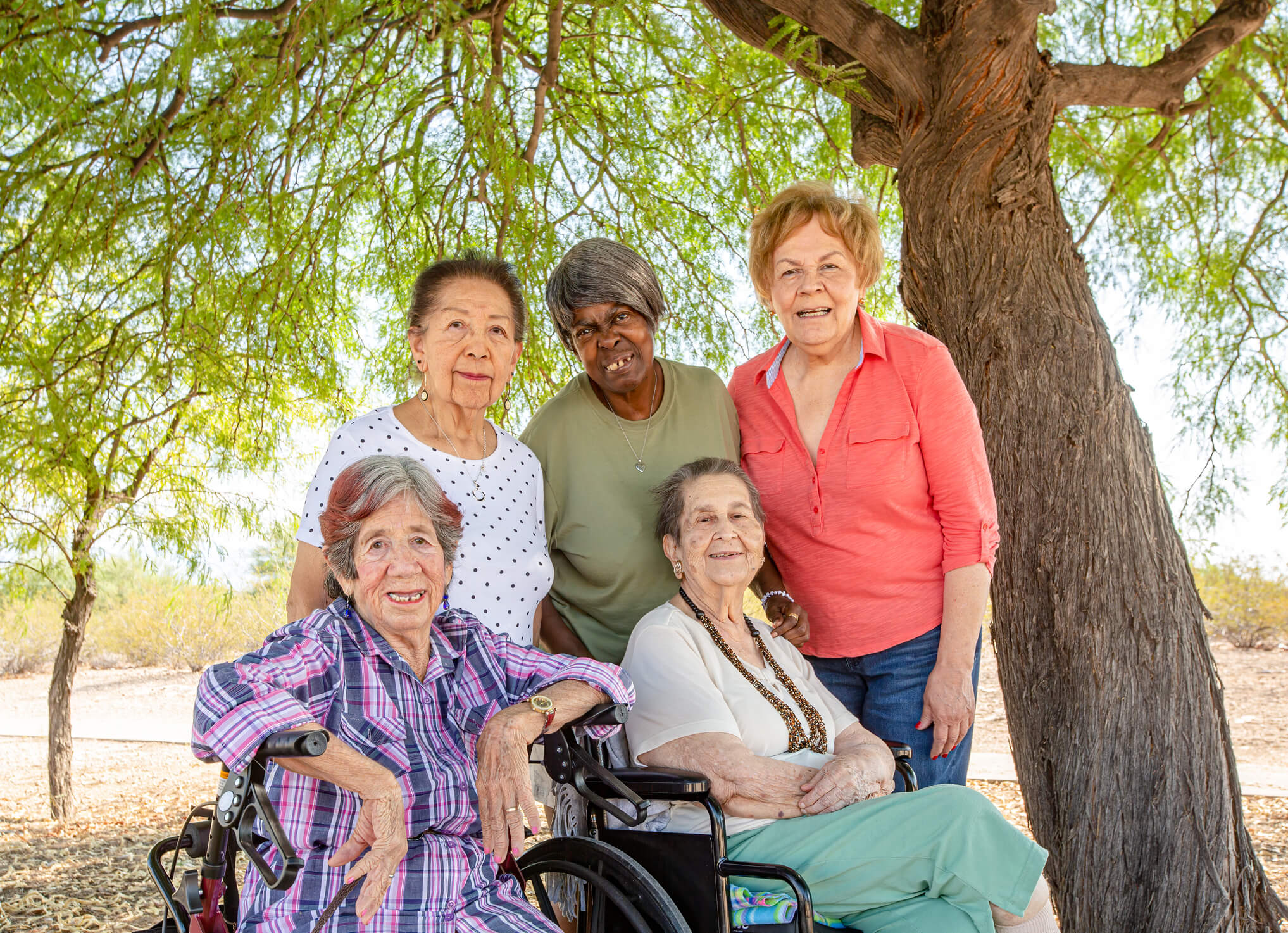 A group of elderly women in wheelchairs posing for a photo.